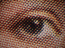 A close-up image of an eye printed in a halftone pattern, showing overlapping red, yellow, blue, and black dots.